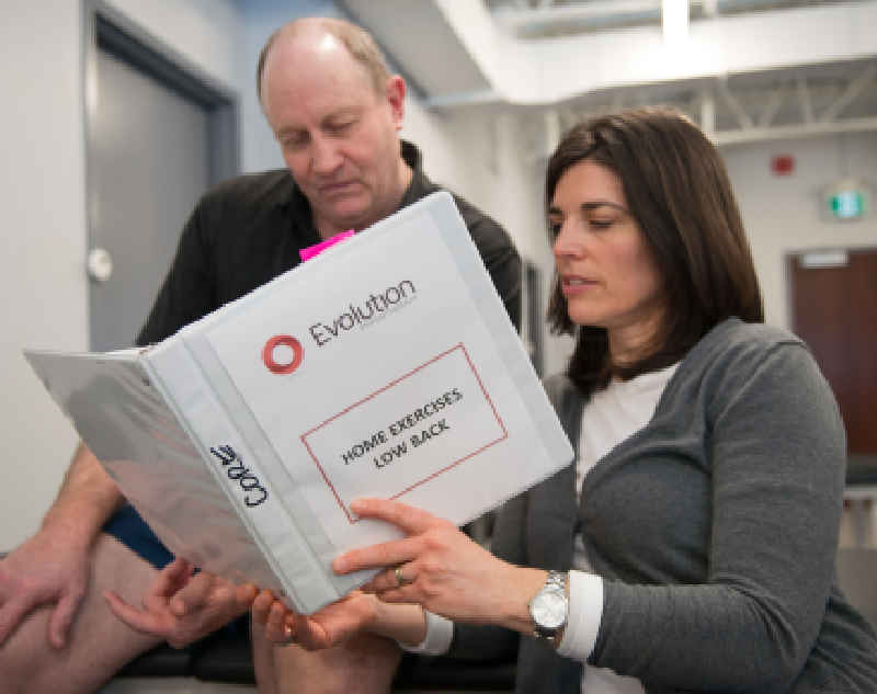 a man and a woman sitting next to each other, both holding a large book or a binder