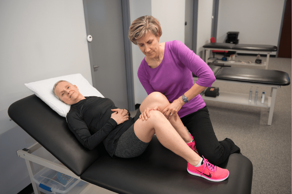 a woman lying on a massage table, receiving a massage from another woman